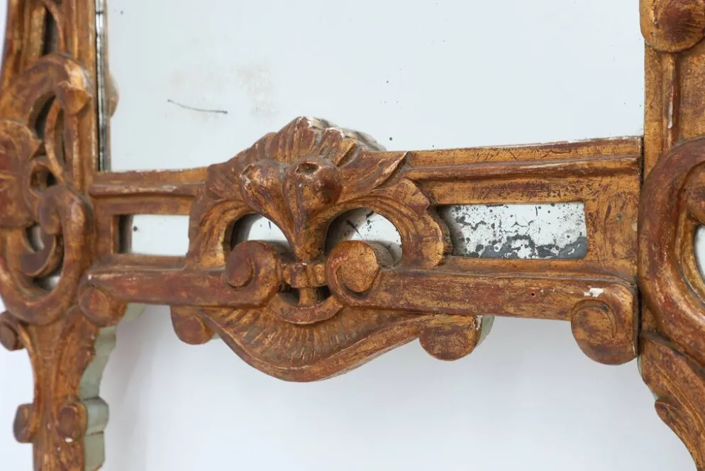 Miroir en bois doré sculpté de style Louis XV avec un fronton floral, France, 18ème siècle.