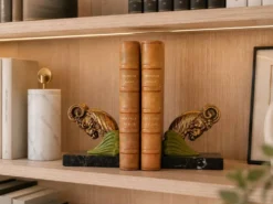 Paire de serre-livres Art Déco têtes de bélier, métal patiné et marbre noir