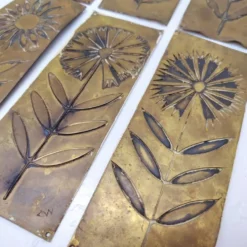 Six plaques de propreté, décor fleurs, laiton
