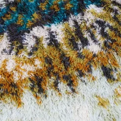 Tapis Rya en laine beige, marron et turquoise.